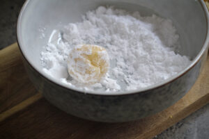 rolling lemon cookie in sugar 